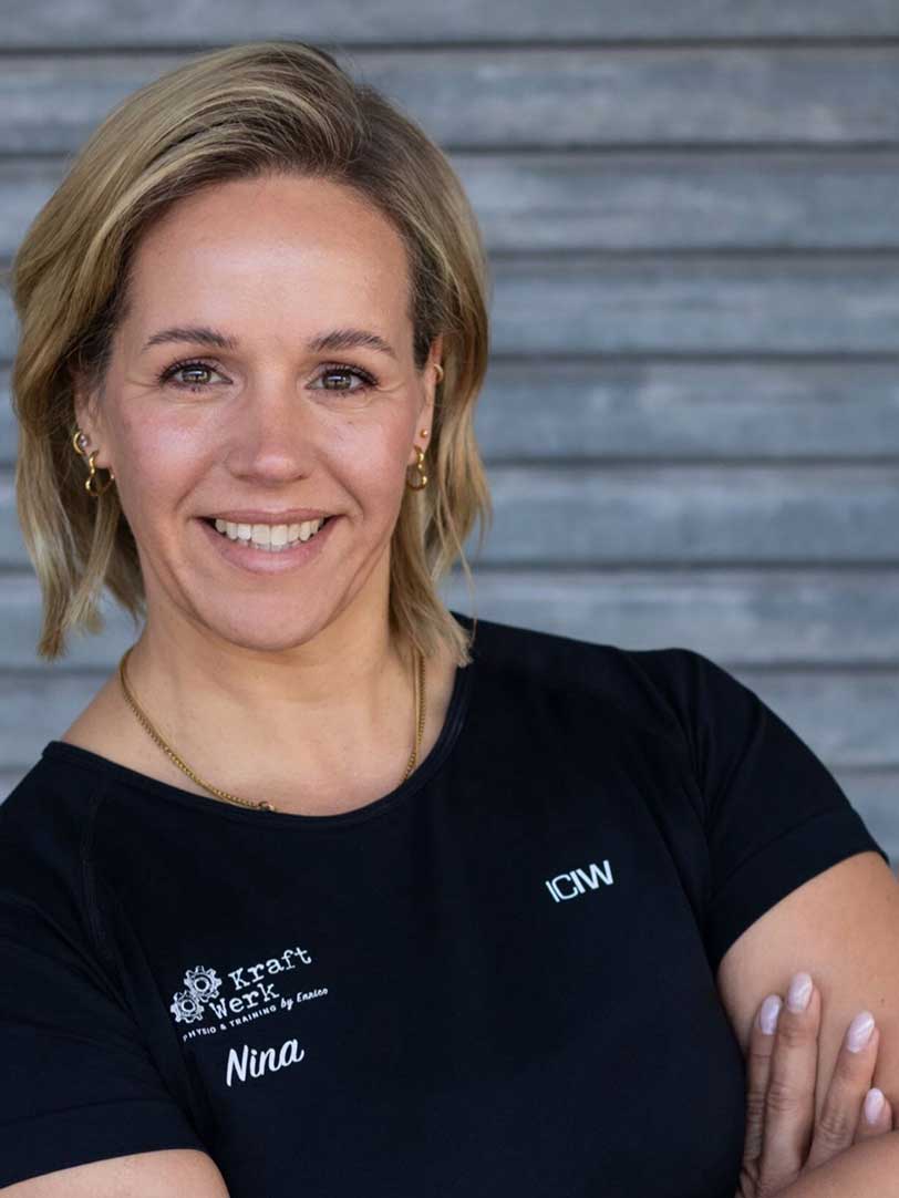 Eine lächelnde Frau mit kurzem blondem Haar in einem schwarzen Shirt.